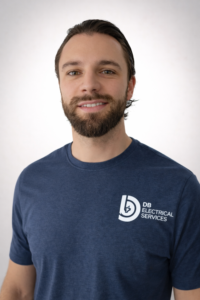 Man with beard wearing a navy t-shirt featuring "DB Electrical Services" logo, representing qualified electricians for consumer unit upgrades and fault diagnosis in Maidenhead.