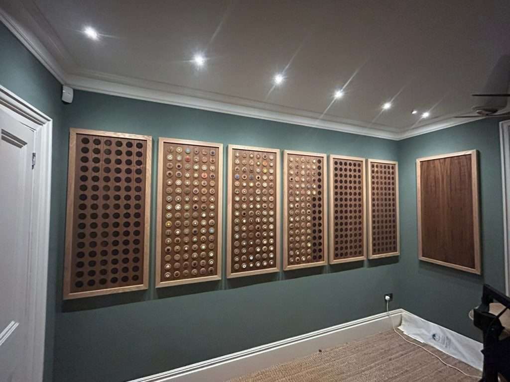 LED downlights illuminating wooden panel wall display featuring various light switches and sockets, showcasing DB Electrics' lighting installation work in a residential setting.