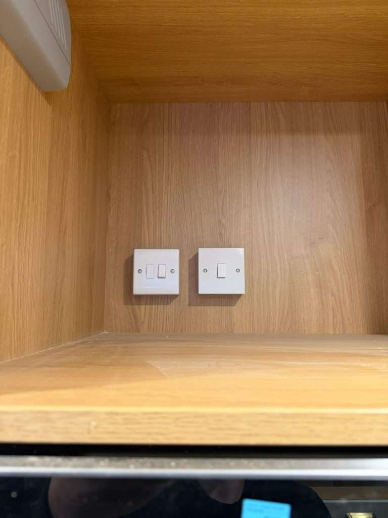 Double light switches installed on wooden wall in a kitchen setting, illustrating socket and switch installation services by DB Electrics in Maidenhead.